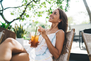 Young woman smiling with iced tea, embracing digital simplicity and joyful pause from mobile work...