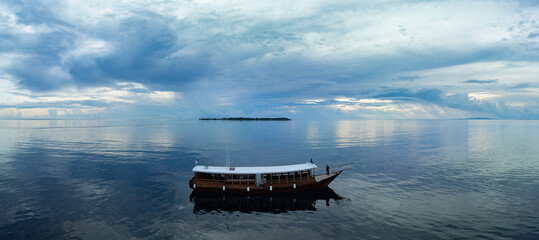 A dive boat drifts along the edge of a reef within Wakatobi National Park, off the coast of Sulawesi. This area is a popular destination for divers and snorkelers due to its high marine biodiversity.