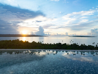A serene sunrise silhouettes an island within Wakatobi National Park, off the coast of Sulawesi. This area is a popular destination for divers and snorkelers due to its high marine biodiversity.