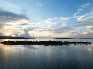 A serene sunrise silhouettes an island within Wakatobi National Park, off the coast of Sulawesi. This area is a popular destination for divers and snorkelers due to its high marine biodiversity.