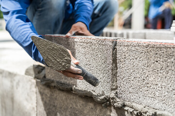 Hand worker masonry brickwork trowel construction site wall concrete background