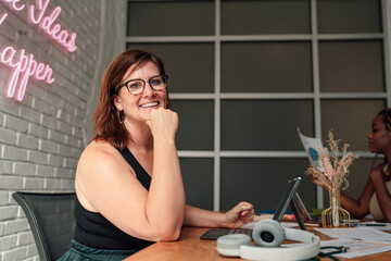 Mature female freelancer types on detachable keyboard, integrating data sheets and tablet into one efficient digital workflow, symbolizing agile thinking and mobile independence.