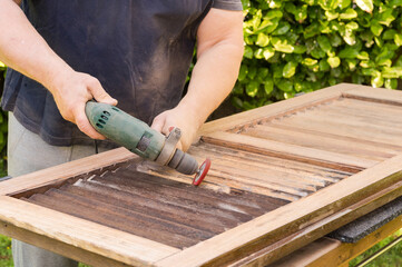 Sanding the wooden shutter using a nylon brush attachment on the drill.
