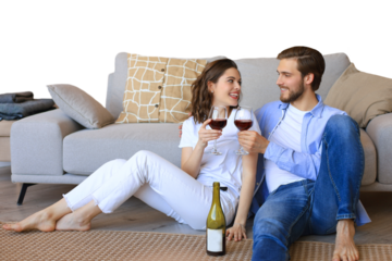 Happy couple sitting, relaxing on floor, drinking red wine. Smiling young husband and wife rest enjoy romantic date on family weekend together on a transparent background