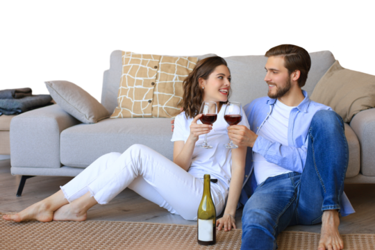 Happy couple sitting, relaxing on floor, drinking red wine. Smiling young husband and wife rest enjoy romantic date on family weekend together on a transparent background - Powered by Adobe