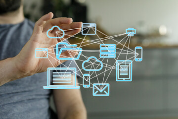 Image depicts a person connecting various devices via a digital network.  Cloud storage and data...