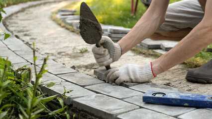 Laying paving stones on cement mortar. Laying a garden path made of tiles. Self-laying of concrete paving slabs in the courtyard of the house. do it yourself. DIY