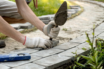 Laying paving stones on cement mortar. Laying a garden path made of tiles. Self-laying of concrete paving slabs in the courtyard of the house. do it yourself. DIY