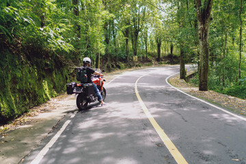 Tattooed rider adjusting GPS route on handlebar-mounted smartphone while stopped, showcasing mobile...