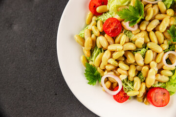 Bean salad green leaf lettuce, tomato, onion vegetables dish fresh delicious gourmet food background on the table rustic food top view copy space keto and paleo diet vegan and vegetarian food
