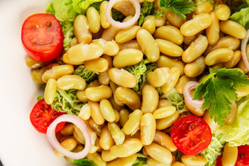 Bean salad green leaf lettuce, tomato, onion vegetables dish fresh delicious gourmet food background on the table rustic food top view copy space keto and paleo diet vegan and vegetarian food