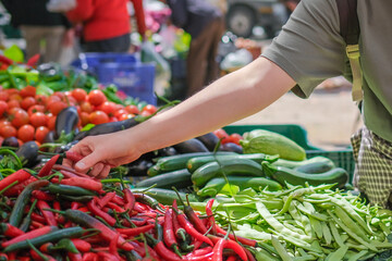 Young woman choosing fresh organic vegetables at a local market. Concept of eco lifestyle,...