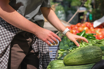 Young woman choosing fresh organic vegetables at a local market. Concept of eco lifestyle, sustainable food, mindful consumption, zero waste, farm produce, and conscious living.