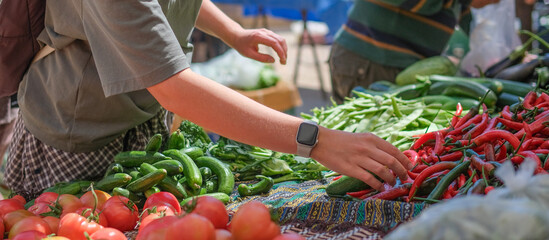 Young woman choosing fresh organic vegetables at a local market. Concept of eco lifestyle,...