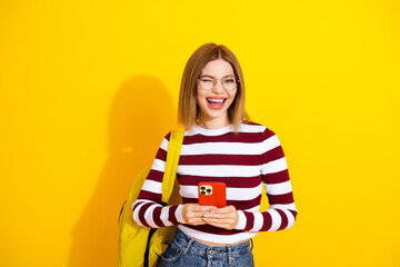 Young woman with blonde hair in striped pullover enjoying moments while using a smartphone,...