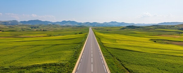 Construction infrastructure highway progress concept. Wide-open road stretching through lush green fields and distant mountains.
