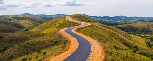 Construction infrastructure highway progress concept. Winding road through scenic hills under a cloudy sky.