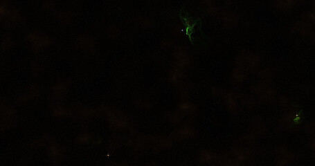 A dark space scene with faint stars and two green nebulae, one larger and one smaller, adding a touch of color to the vast cosmic expanse.