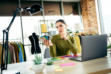 Young businesswoman in atelier workspace analyzing textile samples for creative fashion design...