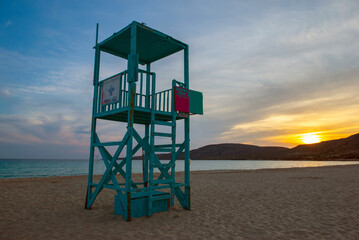 turquoise blue lifeguard high chair on the beach Simos on the island of Elafonisos with sunset in peloponnese , Greece