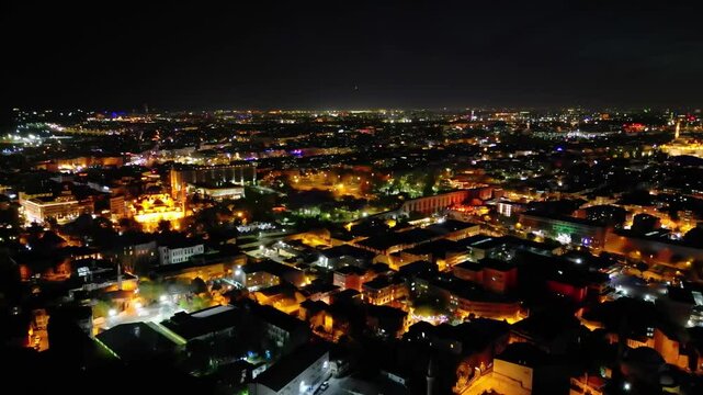 Aerial panorama of Istanbul at night in a half-circle sweep. The city glows with life. Modern buildings and ancient landmarks shimmer under urban lighting.