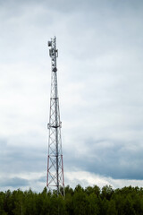 Cell tower rising above forest under cloudy sky, symbol of modern communication in natural landscape