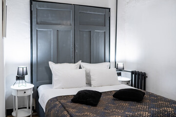 Hotel bed with dark bedspread and white pillows, elegant and inviting atmosphere in a cozy room