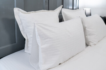 Soft white pillow and padded headboard in hotel bedroom, clean and cozy atmosphere