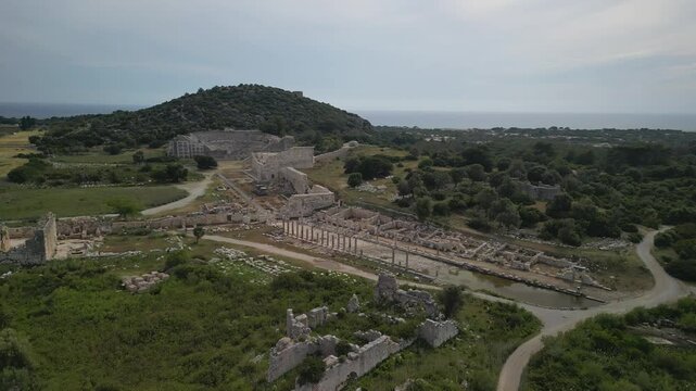 Overview of Patara ruins in Turkey. Columns, roads, and walls. Coastal ancient city in Turkiye. Drone reveals urban layout. Historical importance from Lycian period.