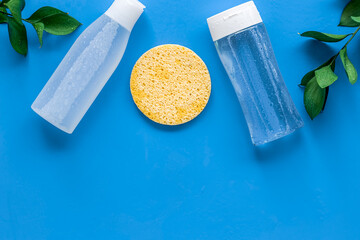 skin care cosmetics with facial tonic, mycelial water and sponge on blue background top view mockup