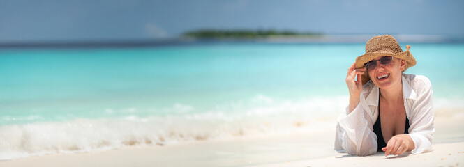 banner portrait woman relax on summer resort, lying on sandy beach wearing straw hat and white shirt, bright sunny tropical atmosphere in maldives, island vacation, summer happiness, copyspace