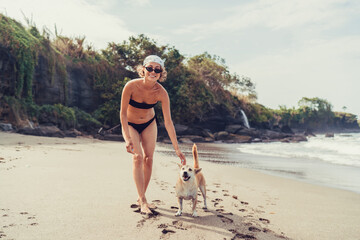 A cheerful capture: woman with tote and phone gear glances back, dog by her side, the...