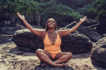 Woman sits cross-legged, arms wide open, embracing spiritual reconnection and tech detox as a form...
