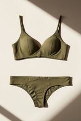 Olive green bra and underwear set on neutral surface, natural sunlight and soft shadows, minimalist, modern, stylish display.