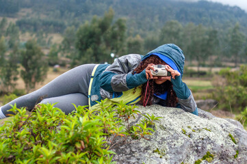 Photographer lying on rock taking pictures in the rain.Photography day