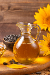 Sunflower oil and sunflower seeds on traditional rustic wooden background. Organic and eco food concept. Healthy food and fats.