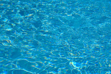 Clear turquoise swimming pool water surface with sunlight reflections
