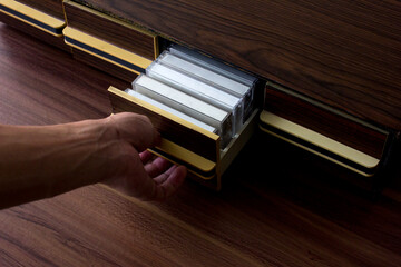 Pulling a drawer containing a collection of cassette tapes. These cassette tapes have blank white...
