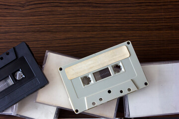 A gray cassette tape with a blank label and several other tape cassettes on a wooden board.