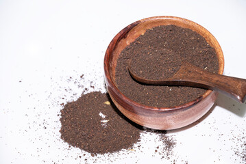 black tea powder in the wooden spoon isolated on white background. tea powder tea leaf after...