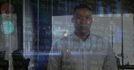 Facing camera man wearing shirt in office corridor, with stock ticker displays and briefcase