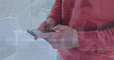 Holding smartphone, man in red sweater analyzing market charts at desk, with data overlays
