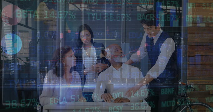 Collaborating team meeting around wheelchair user at modern office desk, with stock market graphics