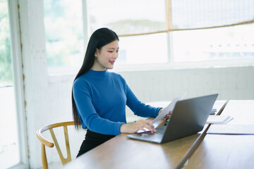 Focused Professional Woman: A young businesswoman sits at her desk, meticulously reviewing...