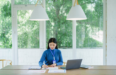 Portrait young asian businesswoman working on laptop at office, smiling and happy working.