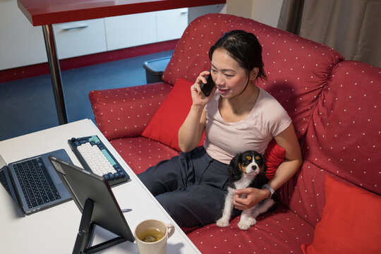 Asian woman multitasking with her puppy at home
