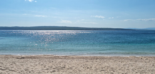 A view from the sandy Poli Mora beach in Selce, with shimmering turquoise sea in the foreground and...