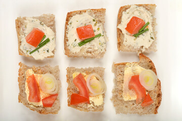 Vegan open-faced sandwiches: three with vegan cheese with herbs, and three with vegan butter with truffle powder, arranged on a white tray.