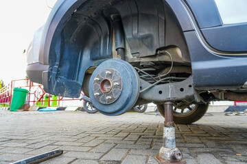 Replacing Car Tire with Jack on Brick Pavement in Outdoor Setting