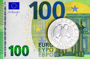 Silver coin three Russian rubles on the background of a paper banknote 100 euros. Money of the European Union